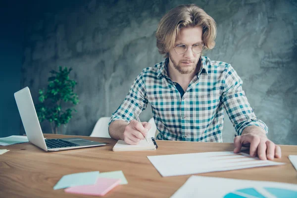 Retrato de empresário concentrado com projeto de escrita de cabelo loiro vestindo óculos de óculos xadrez camisa xadrez sentado em industrial — Fotografia de Stock