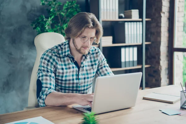 Portrait of concentrated guy typing looking modern technology wearing checkered plaid shirt eyewear eyeglasses sitting in industrial — Stock Photo, Image