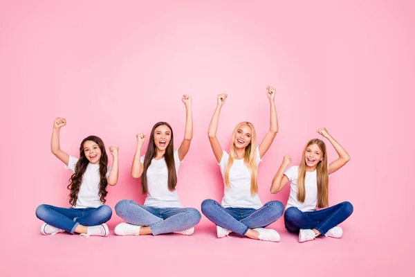 Nice attractive lovely cheerful cheery glad positive confident girls sitting on floor crossed legs celebrating good news rising hands up rejoice solution isolated over pink pastel background — Stock Photo, Image