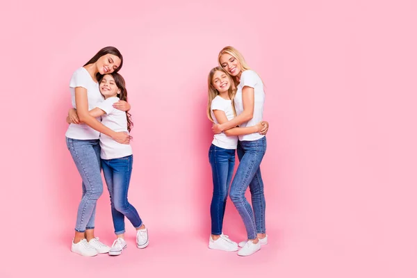 Фотография в полный рост четырех дам разных возрастов, обнимающихся от радости, в повседневном наряде на изолированном розовом фоне — стоковое фото