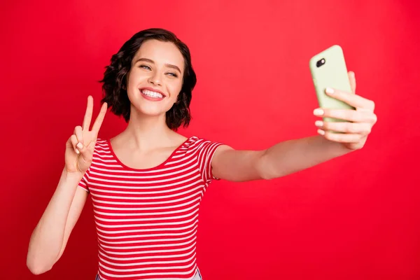 Retrato de ella ella atractiva atractiva guapo alegre alegre alegre amigable ondulado de pelo chica tomando haciendo selfie mostrando v-signo aislado sobre brillante brillante brillo rojo fondo —  Fotos de Stock