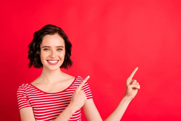 Close-up portrait of her she nice attractive lovely pretty charming cheerful cheery glad content wavy-haired lady pointing two forefingers aside ad advert isolated on bright vivid shine red background — Stock Photo, Image