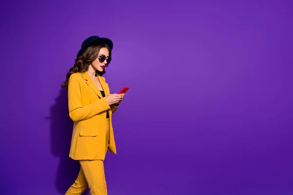 Hübsche Dame hält Hände Telefon zu Fuß nach Hause tragen Spezifikationen gelb Kostüm isoliert lila Hintergrund — Stockfoto