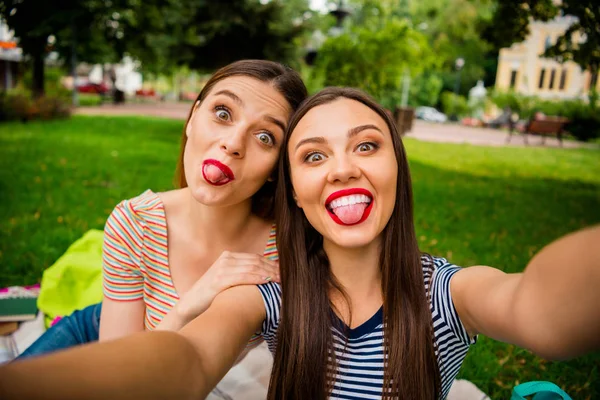 Foto de cerca de la juventud pelirroja haciendo fotos engañando sentado en manta a cuadros con camisetas a rayas vaqueros — Foto de Stock