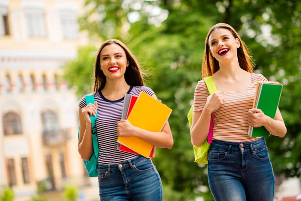 Porträtt av glada damer med rött läppstift hålla anteckningsböcker bär randig t-shirt denim jeans i stan utomhus — Stockfoto