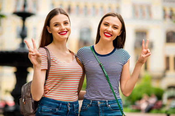 Retrato de amigos sonhadores com cabelos vermelhos morena ter sorriso de dente fazendo v-sinais vestindo listrado t-shirt jeans ganga na cidade fora — Fotografia de Stock