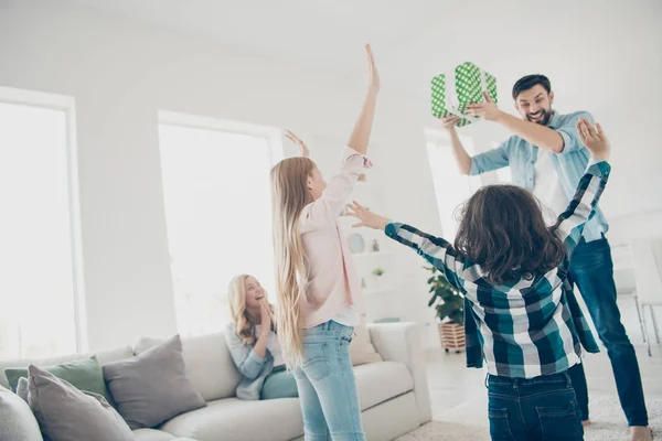 Фото молодої прийомної сім'ї двоє дітей, які піднімають руки, отримують несподівану подарункову коробку з радістю мати найкращих батьків — стокове фото