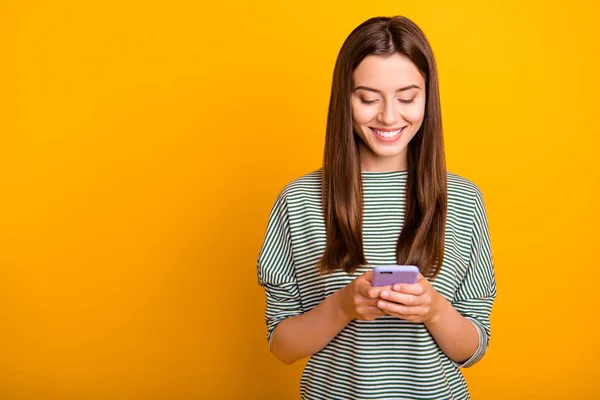 Foto van opgewonden vrolijke vriendin bladeren door haar favoriete pagina van een aantal sociale media, terwijl geïsoleerd met gele achtergrond — Stockfoto
