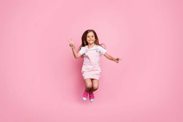 Teljes hosszúságú fotó kis csodálatos hölgy jumping magas v-jel szimbólum hétvégi hangulat kopás v. ruha cipő elszigetelt rózsaszín háttér — Stock Fotó