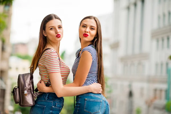 Back side photo of chic ladies sending air kisses wearing striped t-shirt denim jeans rucksack in town outside — Stock Photo, Image