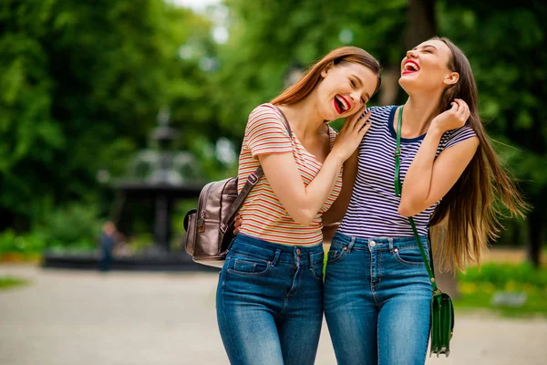 Portrait of cheerful buddies with closed eyes red lips laughing wearing striped t-shirt denim jeans in town outside — Stock Photo, Image