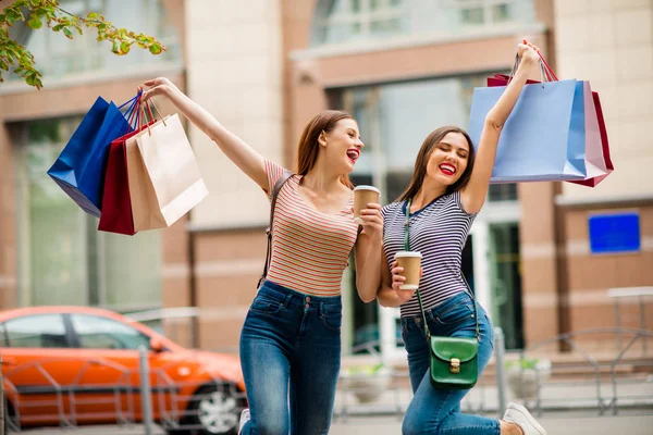 Portret zachwyconych dziewcząt z czerwoną brunetką włosy pomade trzymając plecak w torebce cappuccino w paski t-shirt Jeans denim w mieście na zewnątrz — Zdjęcie stockowe