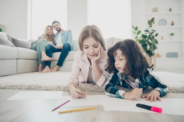 Fotó a nagy család két gyermek fekvő padlón bolyhos szőnyeg hogy rajzokat, míg a szülők élvezik néz barátságos örökbe fogadott gyermekek — Stock Fotó