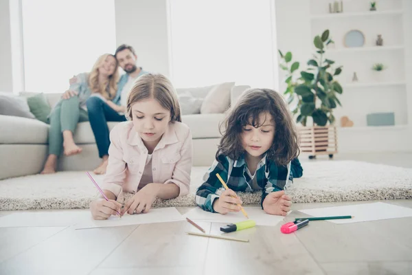 Photo of big family two children comfortable lying floor fluffy carpet making drawings while parents sit sofa — Stock Photo, Image