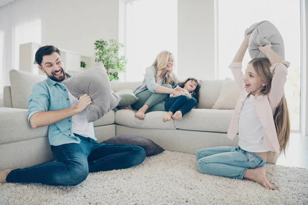 Foto de família adotiva quatro membros passam o tempo de lazer regozijando travesseiros luta rir sentar sofá sala de estar — Fotografia de Stock