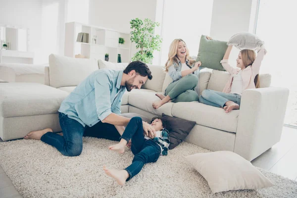 Foto da família adotada quatro membros passam o tempo livre travesseiros luta rir sentar sofá sala de estar — Fotografia de Stock