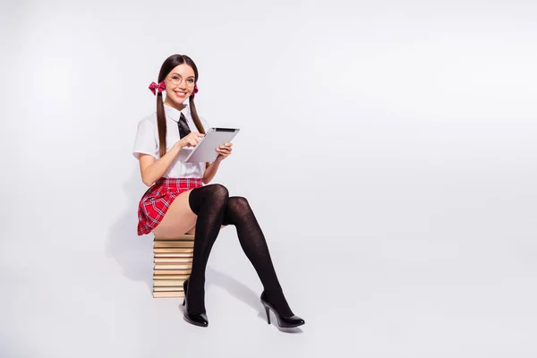 Πλήρες μήκος σώματος φωτογραφία όμορφη αυτή δασκάλα της καθίσει βιβλίο αναζήτηση πληροφοριών εργασία e-Book εξαπάτηση εξέταση φορούν προδιαγραφές σύντομο κόκκινο καρό κοστούμια καλσόν καλσόν απομονωμένη λευκό φόντο — Φωτογραφία Αρχείου