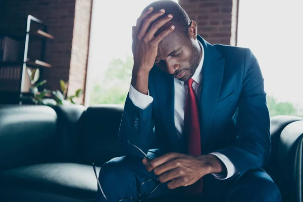 Foto von dunkelhäutigen Kerl sitzen Büro Sofa halten Kopf auf der Hand fühlen sich schwindelig tragen elegante Kostüm — Stockfoto