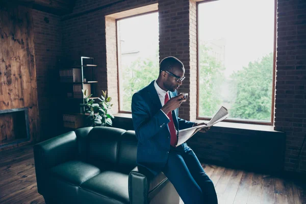 Dunkle Haut Macho-Typ lehnt Büro-Sofa trinken Heißgetränk lesen frische Presse tragen elegante Kostüm — Stockfoto