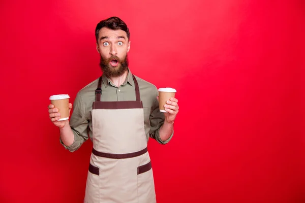 Retrato de su agradable atractivo confundido sorprendido sorprendido barbudo camarero tipo sosteniendo en las manos capuchino café espresso latte elegir opción aislado sobre brillante vivo brillo fondo rojo — Foto de Stock