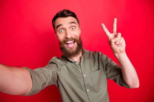 Foto del hombre tomando selfie que muestra v-signo con su rostro asombrado mientras está aislado con fondo rojo — Foto de Stock