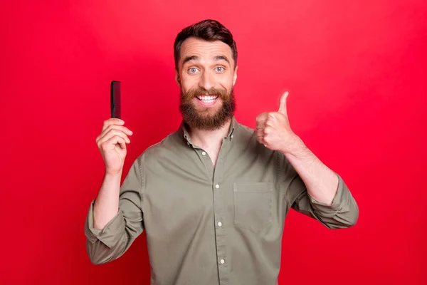 Foto pria yang mengiklankan sikat rambut menunjukkan bahwa ia suka menggunakan hal ini sementara terisolasi dengan latar belakang merah — Stok Foto