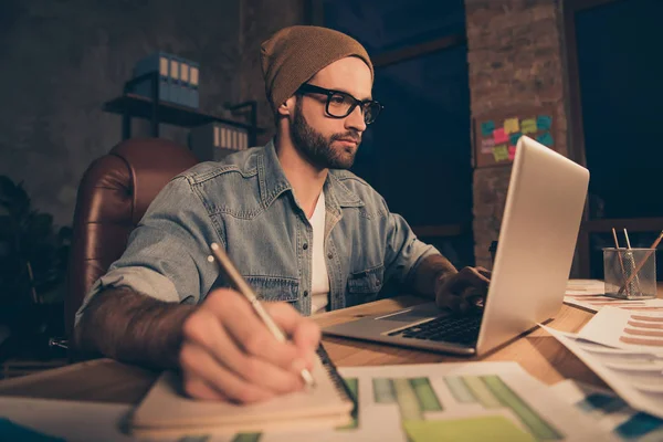 Foto de chico atento trabajo en el tiempo oscuro haciendo notas de la lección en línea desgaste traje casual sentarse oficina moderna —  Fotos de Stock