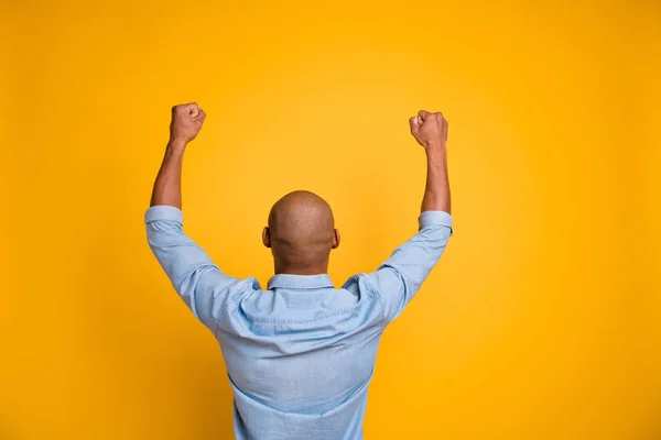 Achter foto van donkere huid Guy opgeheven hands-up ondersteuning favoriete voetbalteam slijtage jeans denim overhemd geïsoleerd fel gele achtergrond — Stockfoto