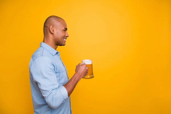 Foto de perfil de piel oscura fresco increíble chico toma de las manos vaso de cerveza permite celebrar el uso de jeans camisa de mezclilla aislado fondo amarillo — Foto de Stock