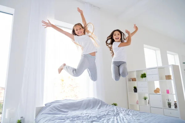 Nízká úhlová fotka veselých dětí skákající do postele mají volný čas zvednout ruku cítit obsah pokoj uvnitř bytu — Stock fotografie
