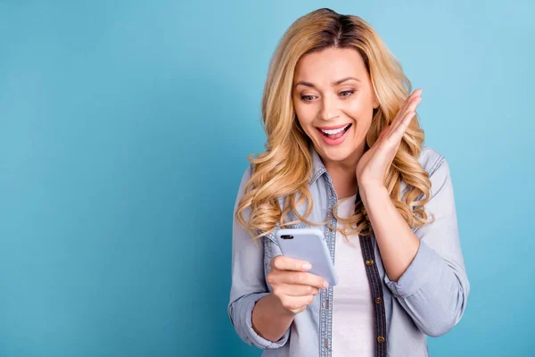 Portrait of astonished lady screaming wow omg holding device isolated reading novelties isolated over blue background — Stock Photo, Image