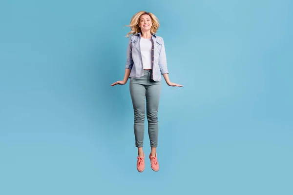 Ganzkörperfoto einer attraktiven hübschen Dame, die mit strahlendem zahmen Lächeln über blauem Hintergrund springt — Stockfoto