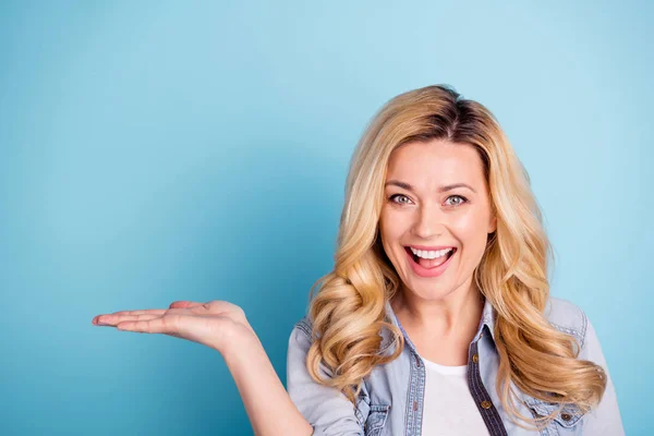 Close up photo of pretty content lady holding hand with promotion isolated over blue background — Stock Photo, Image