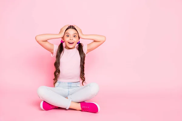 Retrato de niño lindo sentado gritando tocando la cabeza con las manos gritando pantalones blancos vestidos pantalones camiseta aislada sobre fondo rosa — Foto de Stock