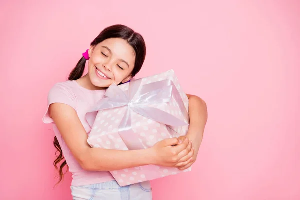 Πορτρέτο του υπέροχο παιδί κρατώντας κουτί δώρου αγκάλιασμα κλείσιμο μάτια φορούν λευκό μπλουζάκι απομονωμένο πάνω από ροζ φόντο — Φωτογραφία Αρχείου