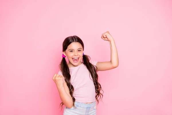 Retrato de menina alegre levantando punhos gritando sim vestindo t-shirt branca isolada sobre fundo rosa — Fotografia de Stock