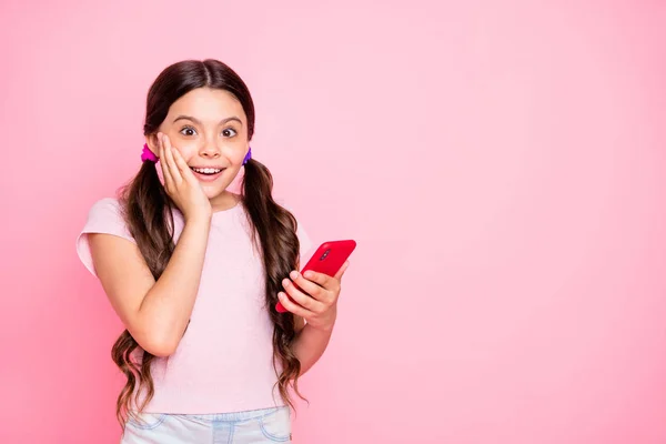 Retrato de niño asombrado sosteniendo dispositivo gritando mejilla táctil con la mano desgaste camiseta blanca aislada sobre fondo rosa — Foto de Stock