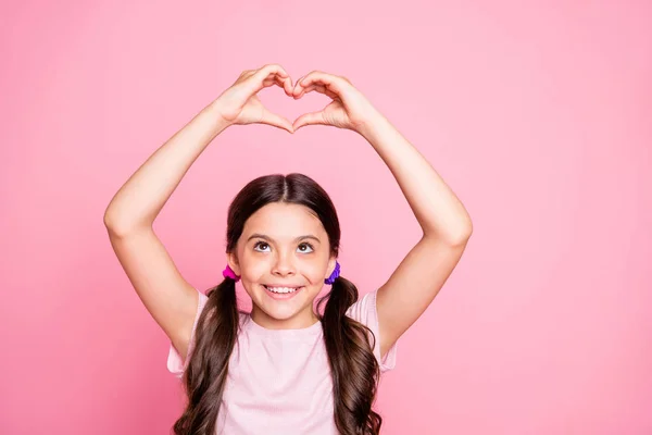 Retrato de meninas bonitos levantando as mãos sorrindo fazendo coração de dedos olhando vestindo t-shirt branca isolada sobre fundo rosa — Fotografia de Stock