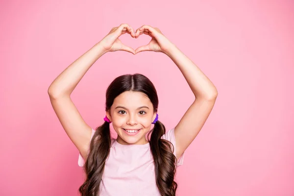 Close up foto de alegre fazer coração de dedos sorrindo vestindo t-shirt branca isolada sobre fundo rosa — Fotografia de Stock