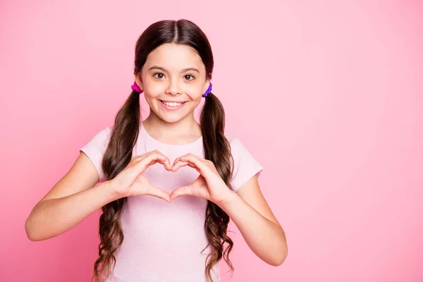 Retrato de criança alegre mostrando coração fazer de dedos sorrir desgaste t-shirt branca isolada sobre fundo rosa — Fotografia de Stock