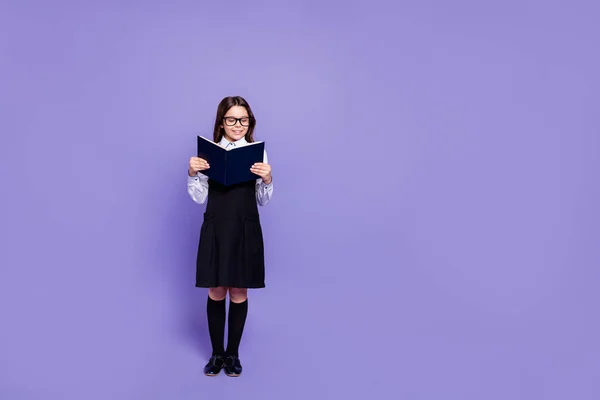 Longitud completa tamaño del cuerpo vista de agradable contenido alegre atractivo diligente cerebro ondulado de pelo preadolescente chica sosteniendo en las manos la lectura de la literatura académica aislado sobre brillante brillo violeta fondo —  Fotos de Stock