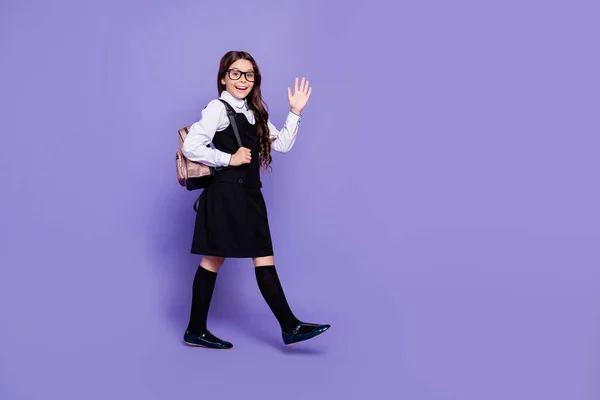 Full length body size profile side view of nice attractive cheerful wavy-haired pre-teen girl going to class waving hi hello good news isolated over bright vivid shine violet background — стоковое фото