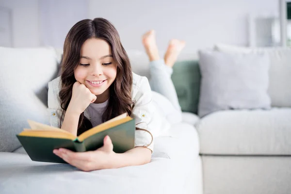 Portret van haar ze mooie aantrekkelijke mooie charmante schattige vrolijke vrolijke gerichte golvende haired Preteen meisje liggend op Divan lezing roman in licht wit interieur woonkamer binnenshuis — Stockfoto