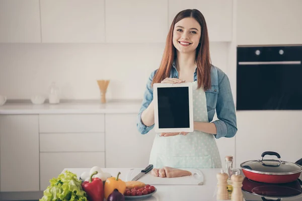 Фото уважної дружини носять пунктирний фартух, який представляє нову модель електронного читання найкраще допомагає кухонним обов'язкам — стокове фото