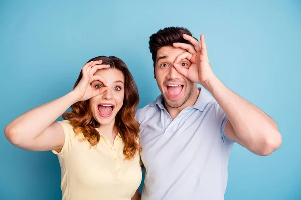 Foto de par funky animado melhores amigos símbolo okey perto de olhos óculos especificações usar casual t-shirts isolado fundo azul — Fotografia de Stock