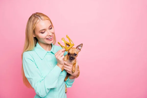 Ritratto di affascinante signora che tiene il suo grazioso animale domestico che mette tiara sulla testa indossando una camicia color menta isolata su sfondo rosa — Foto Stock