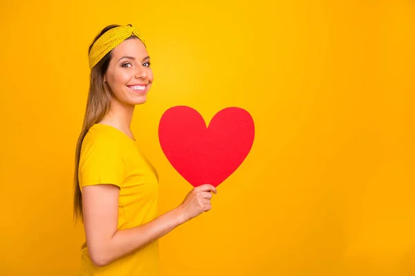 Retrato de senhora encantadora segurando presente para 14-fevereiro olhando para a câmera com sorriso de dente isolado sobre fundo amarelo — Fotografia de Stock