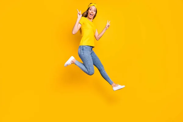 Foto de longitud completa de la hermosa dama saltando alto mostrando símbolo de v-signo de desgaste ropa casual aislado fondo amarillo — Foto de Stock