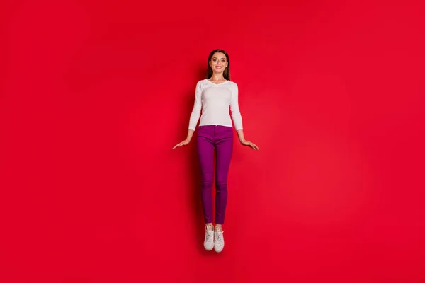 Foto de legal agradável bonito encantador menina pulando para cima voando como foguete enquanto isolado com fundo vermelho — Fotografia de Stock