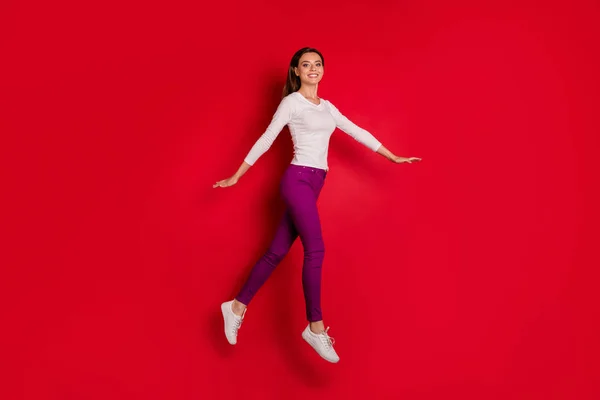 Foto de cuerpo de cuerpo entero de chica deportiva corriendo incluso sin ropa deportiva mientras se aísla con fondo rojo — Foto de Stock